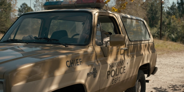 Wide shot frame from Stranger Things — street, car, wheel