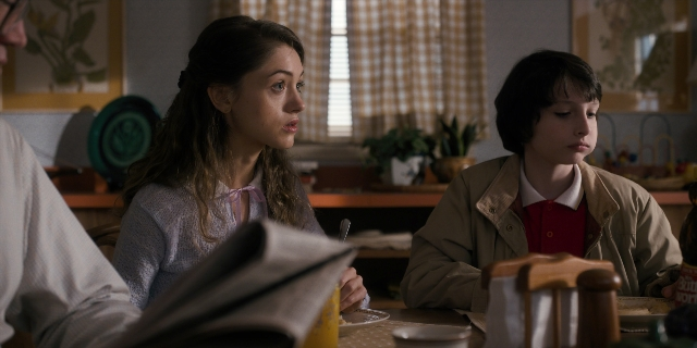 Wide shot frame from Stranger Things — sitting, table, dialogue