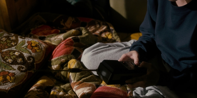Wide shot frame from Stranger Things — sitting, bed, person