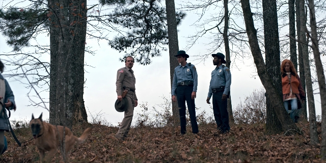 Wide shot frame from Stranger Things — walking, hat, dog