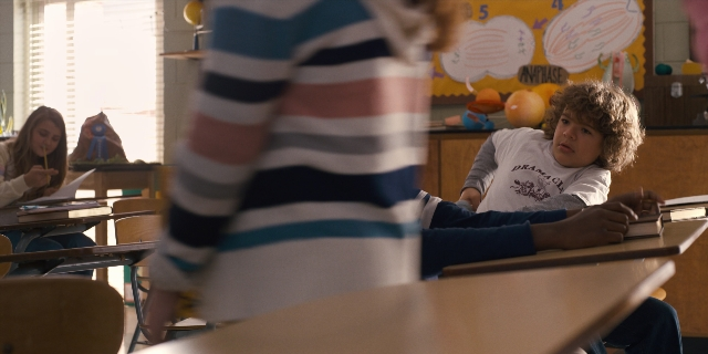 Wide shot frame from Stranger Things — sitting, room, table