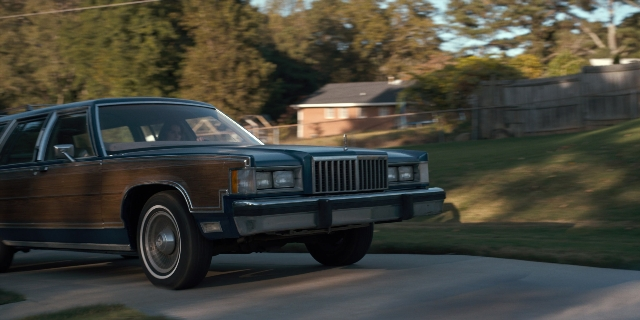 Wide shot frame from Stranger Things — plate, street, car