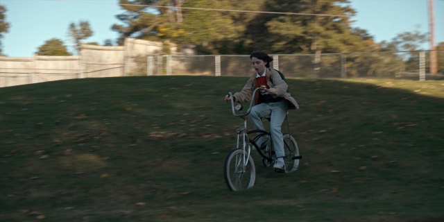 Wide shot frame from Stranger Things — bicycle, person, human face