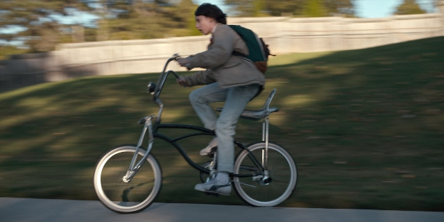 Wide shot frame from Stranger Things — bicycle, backpack, person