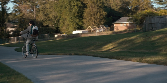 Wide shot frame from Stranger Things — street, bicycle, backpack