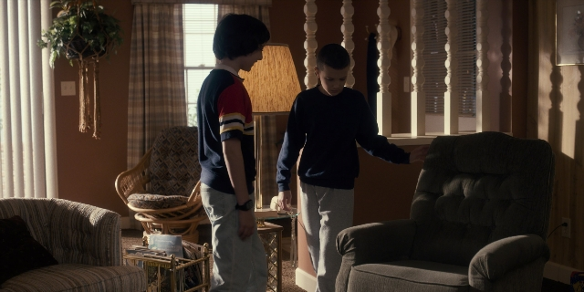 Wide shot frame from Stranger Things — standing, room, table