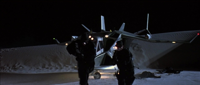 Wide shot frame from Tank Girl — standing, hat, night