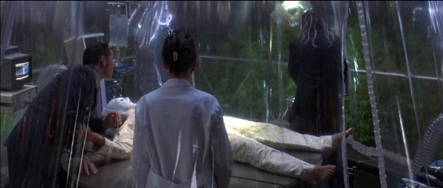 Wide shot frame from Tank Girl — standing, room, bed