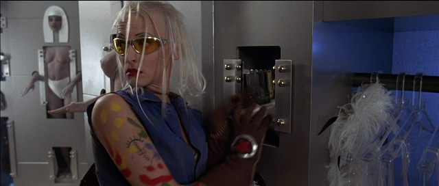 Wide shot frame from Tank Girl — room, door, bathroom