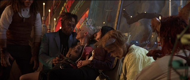 Wide shot frame from Tank Girl — sitting, book, standing