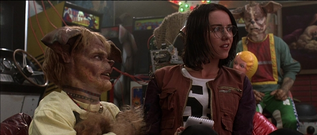 Wide shot frame from Tank Girl — sitting, room, hat