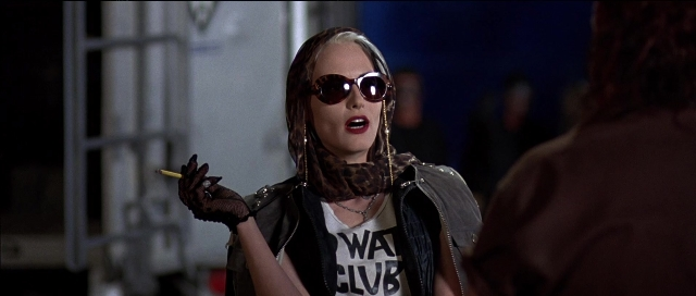 Medium shot frame from Tank Girl — hand, jacket, face