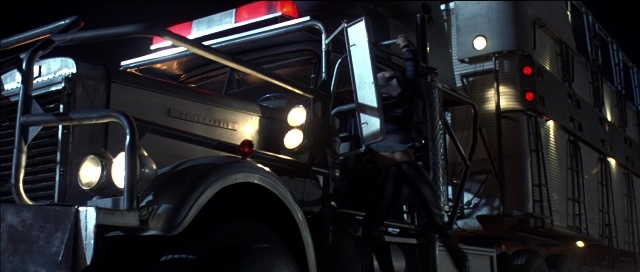 Wide shot frame from Tank Girl — street, fire, night