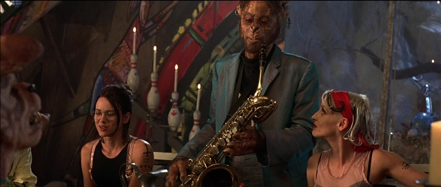 Wide shot frame from Tank Girl — room, suit, face