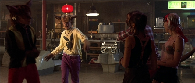 Wide shot frame from Tank Girl — standing, room, dialogue
