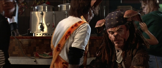 Wide shot frame from Tank Girl — sitting, kitchen, shirt