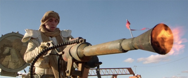 Frame from Mad Max 2 — standing, face, cannon