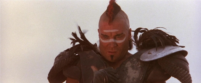 Medium shot frame from Mad Max 2 — hat, bird, fight