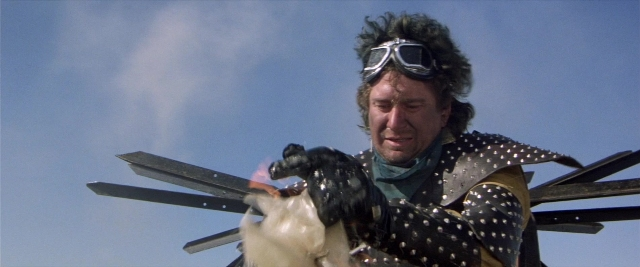 Wide shot frame from Mad Max 2 — hand, face, hair