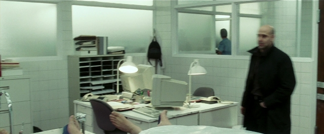 Wide shot frame from Lucky Number Slevin — sitting, desk, standing