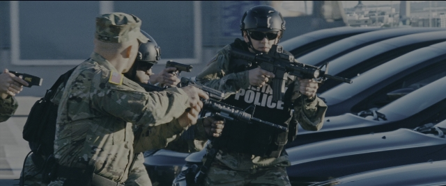 Wide shot frame from Jack Reacher: Never Go Back — standing, hat, car