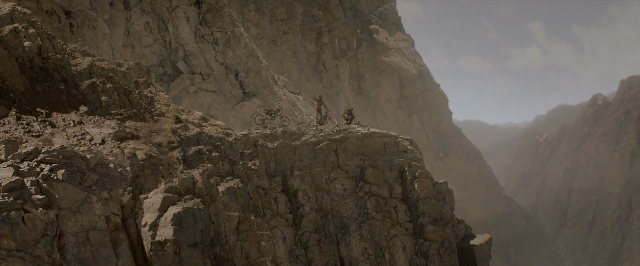 Wide shot frame from Mad Max: Fury Road — bicycle, face