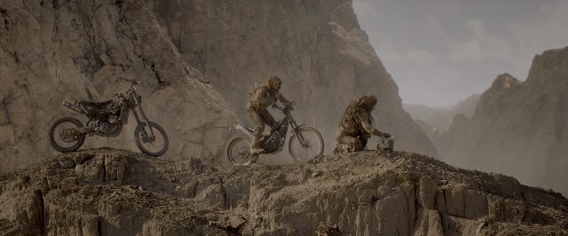 Wide shot frame from Mad Max: Fury Road — bicycle, person, bicycle wheel