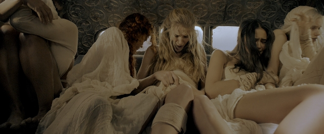 Wide shot frame from Mad Max: Fury Road — sitting, bed, dress