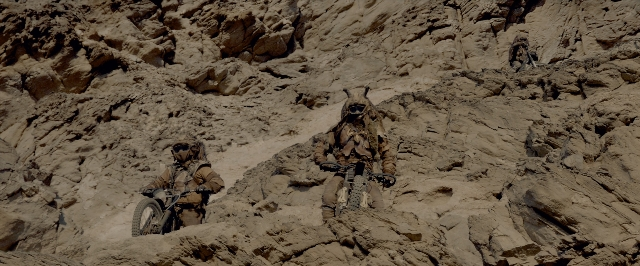 Wide shot frame from Mad Max: Fury Road — hat, bicycle, person
