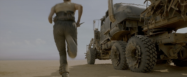 Wide shot frame from Mad Max: Fury Road — walking, bed, car