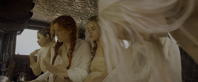 Wide shot frame from Mad Max: Fury Road — sitting, hair, train