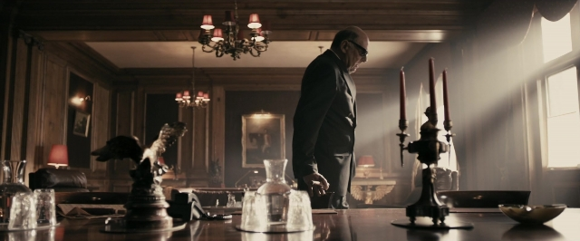Wide shot frame from RocknRolla — standing, room, table