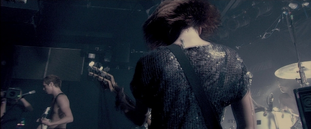 Frame from RocknRolla — standing, dress, microphone
