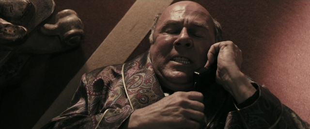 Medium shot frame from RocknRolla — standing, phone, face