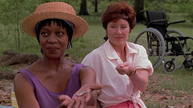 Medium shot frame from Passion Fish — sitting, hat, hand