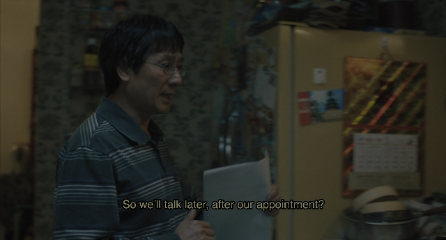 Wide shot frame from Everything Everywhere All at Once — standing, kitchen, hand