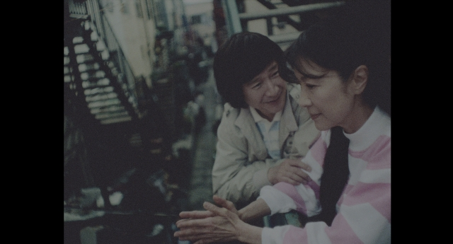 Wide shot frame from Everything Everywhere All at Once — sitting, street, face