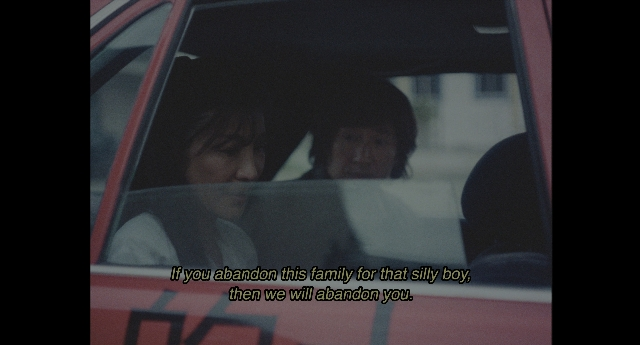 Wide shot frame from Everything Everywhere All at Once — sitting, car, shirt