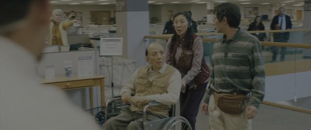 Wide shot frame from Everything Everywhere All at Once — standing, shirt, office