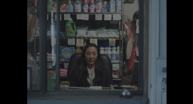 Wide shot frame from Everything Everywhere All at Once — sitting, face, bag