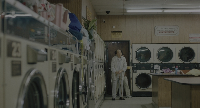 Wide shot frame from Everything Everywhere All at Once — desk, standing, room