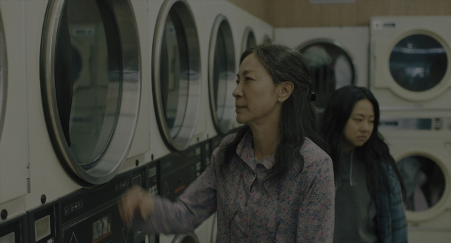 Wide shot frame from Everything Everywhere All at Once — standing, room, hand
