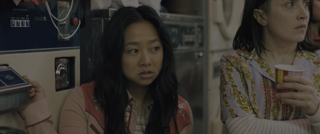 Medium shot frame from Everything Everywhere All at Once — sitting, phone, hand