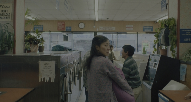 Wide shot frame from Everything Everywhere All at Once — standing, room, dress
