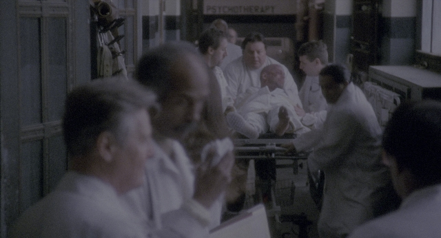 Wide shot frame from Twelve Monkeys — room, dialogue, door