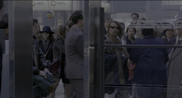 Wide shot frame from Twelve Monkeys — standing, door, glass