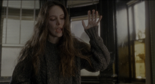Wide shot frame from Twelve Monkeys — standing, room, hand