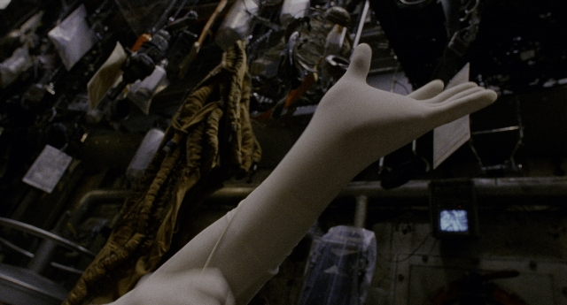 Wide shot frame from Twelve Monkeys — hand, bag, person