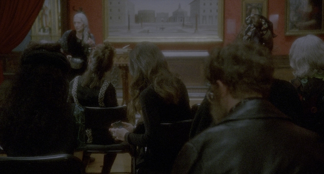 Wide shot frame from Twelve Monkeys — sitting, book, room