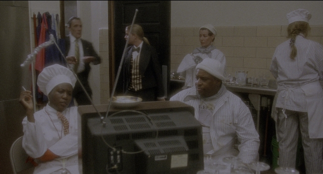 Wide shot frame from Twelve Monkeys — table, kitchen, suit